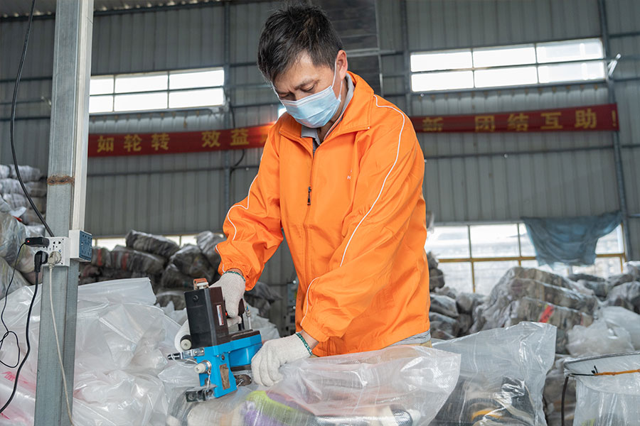 warehouse worker sealing a bale filled with used shoes