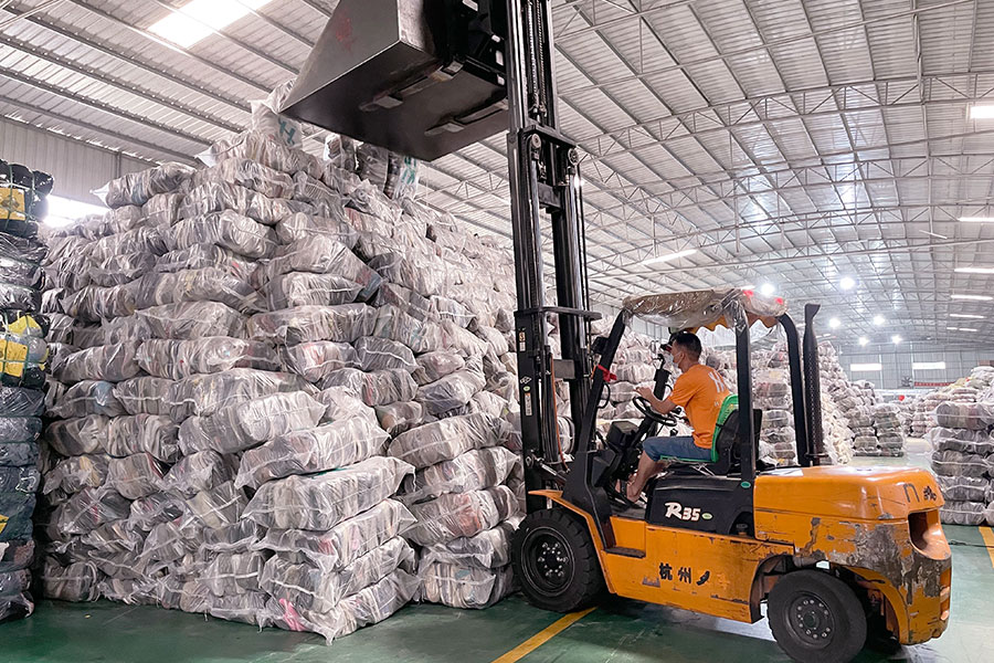 forklift operator stacking piles of used shoe packages