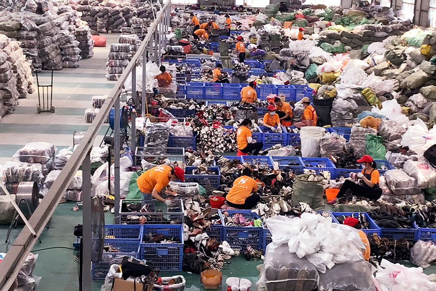 sorters filtering piles of used shoes in the sorting facility